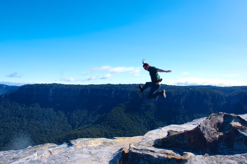 Man jumping in air over blue mountains
