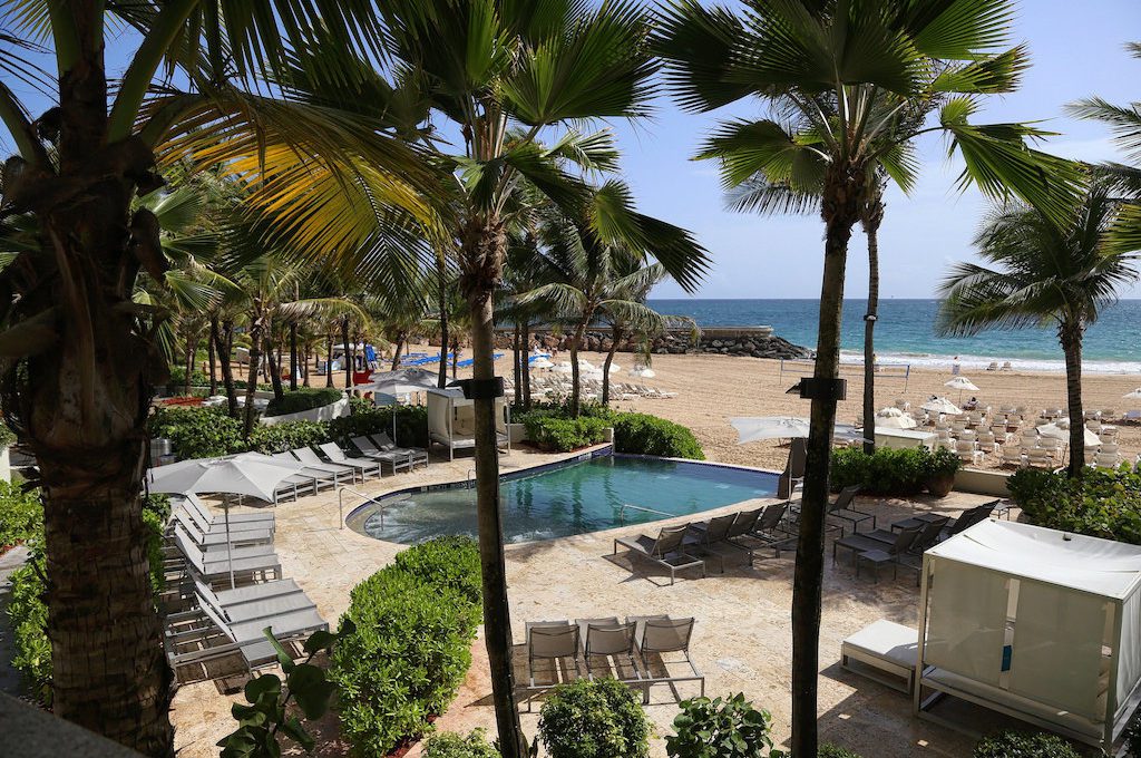 Pool and beach area of hotel with surrounding palm trees