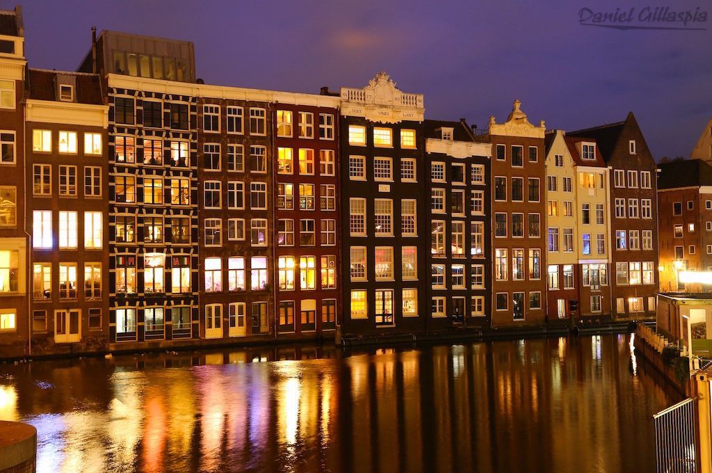 Buildings line canal in Amsterdam at night