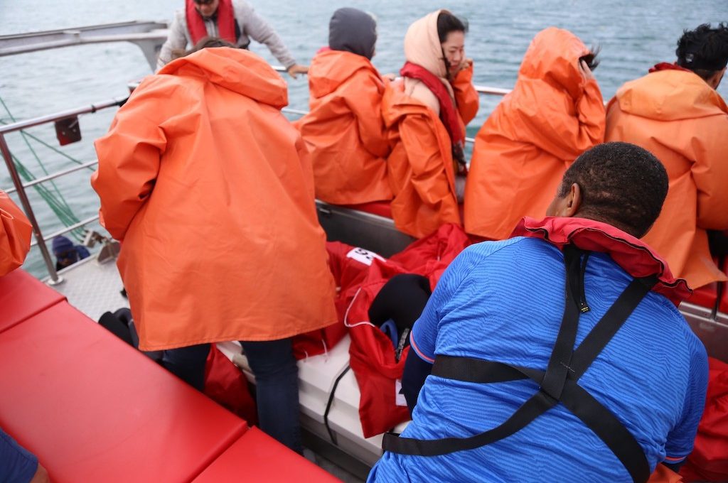 Group of people in orange rain coats on boat