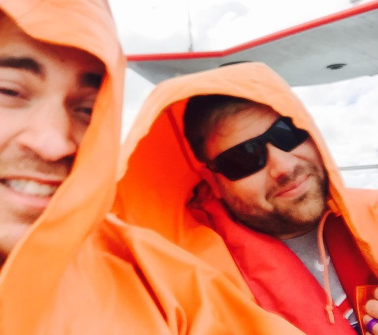 Two men in orange rain coats on boat