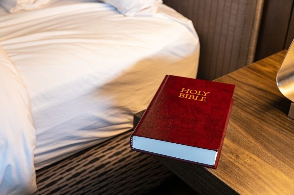 Hotel room with Bible and other amenities on nightstand