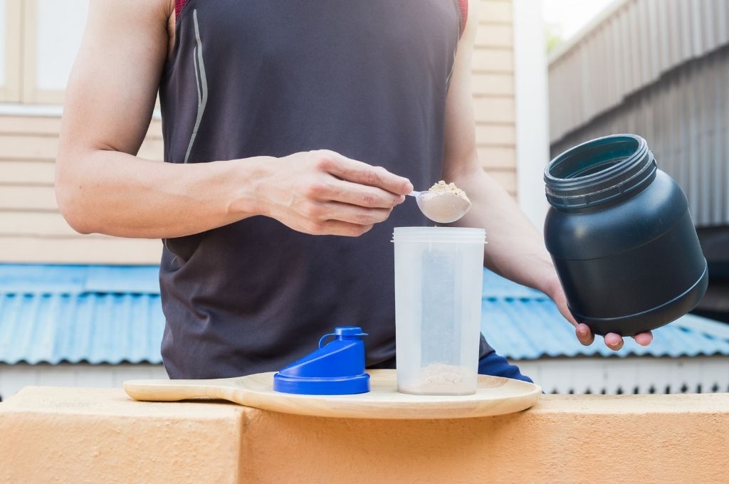 guy scooping protein in shaker bottle