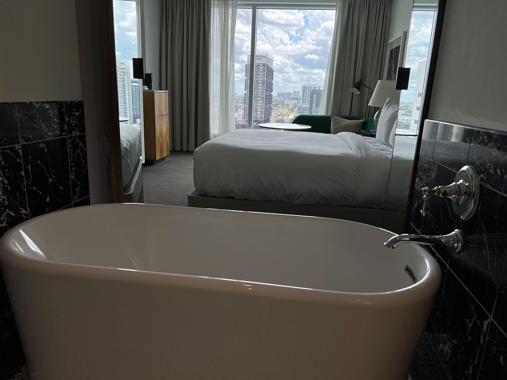 Bath tub with Downtown Houston view in guest room at The Laura Hotel.