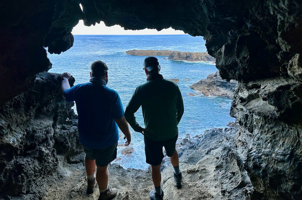Two men standing in Cave over ocean