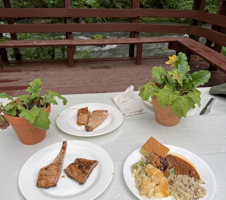 Plates of food by the river at Gold Creek Salmon Bake Juneau