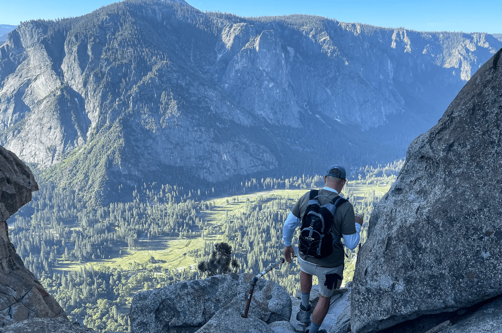 Man walking down trail with valley in distance