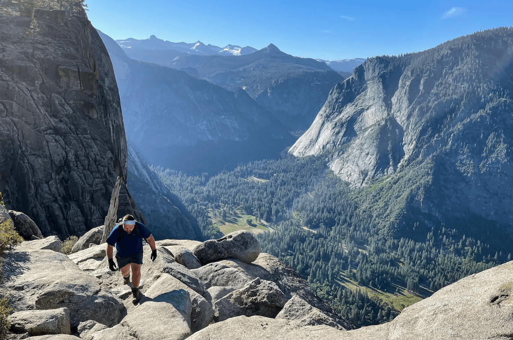 Man hiking up mountain with valley in background