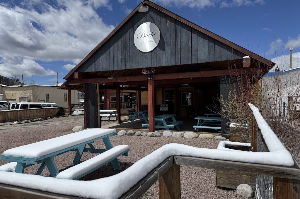 Exterior of black building with snow on tables out front