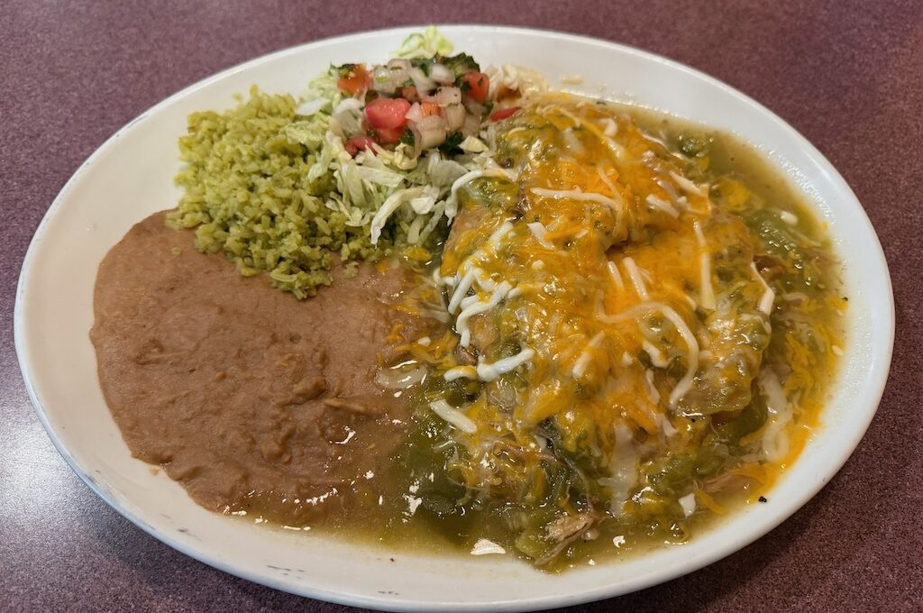 Beef stuffed sopapillas covered in green chili sauce with rice and beans plate