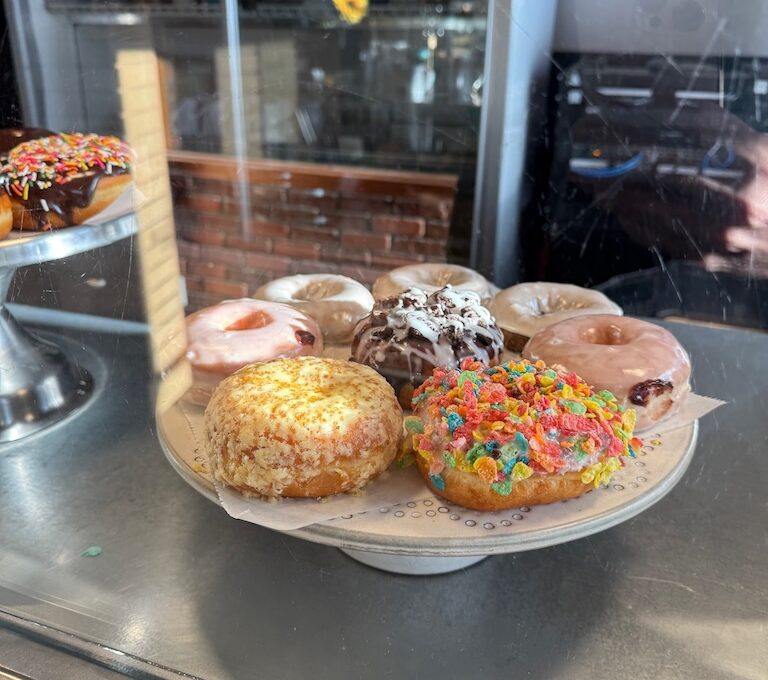 Different donuts on plate in glass case