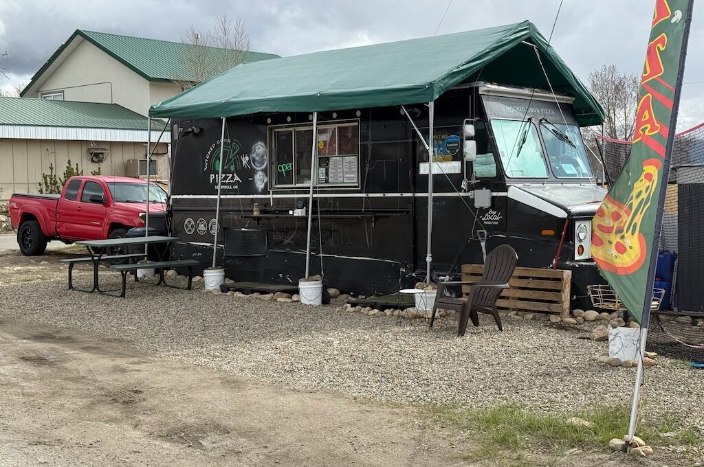Black food truck with green tent on top and red truck