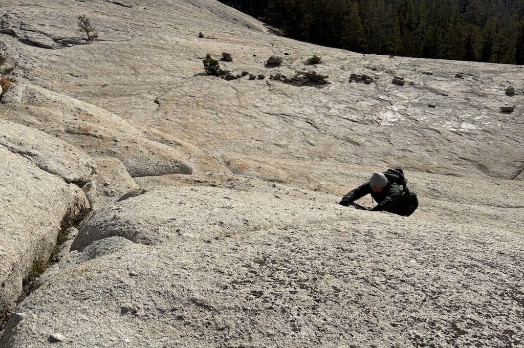 Hiker climbing up rocky mountain slope