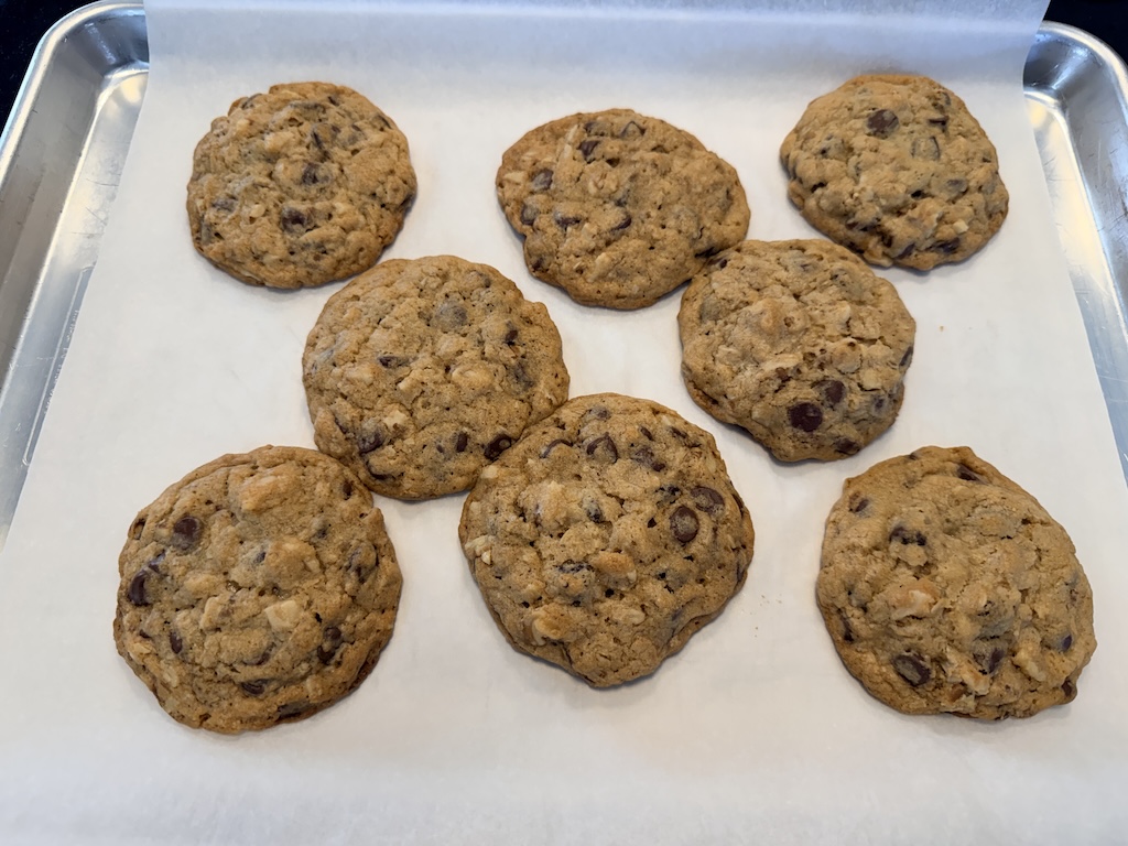 Eight homemade DoubleTree by Hilton cookies on a parchment-lined baking sheet